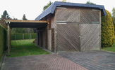 Carport mit einer Holz-Imprägnierung und Schieferverkleidung für einen Wohnwagen; seitlich zusätzlich ein einzelnes Carport