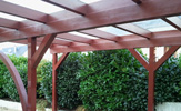 3er-Carport aus Aluminium, Pfosten aus Holz, mit einer Glaseindeckung und einer Kopfbaude zur Stabilität – in Detmold