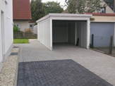 Einzelnes Carport mit einer Aluminium-Kante und einem Garagentor hinter dem Carport – in Detmold