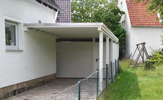 Standard-Carport mit einem Schuppen aus BSH Holz und mit einer Aluminium-Kante und Solux 70/18 Trapezplatten – in Detmold