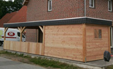 Carport aus Lärchen-Holz mit einer Schieferblende, Aluminium-Kante und einem Geräteschuppen mit Fundamenten – in Olpe